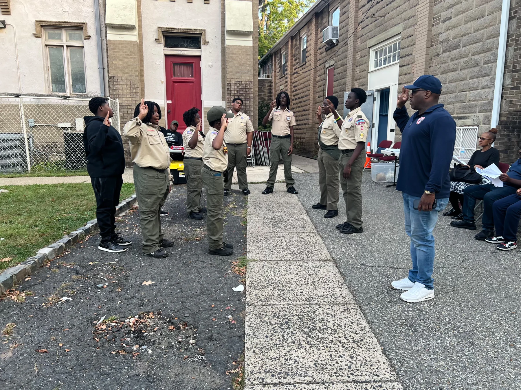 Scouts and adult leaders saluting during an outdoor gathering