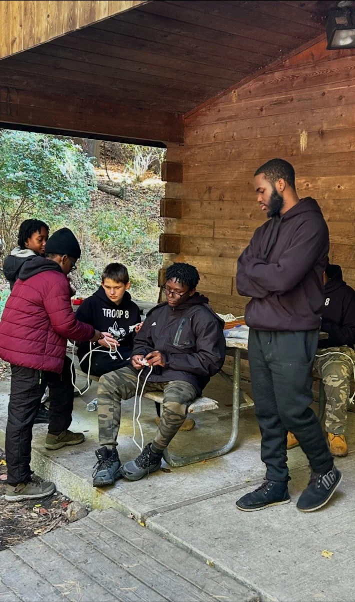 Scouts practice tying knots together with an adult leader.